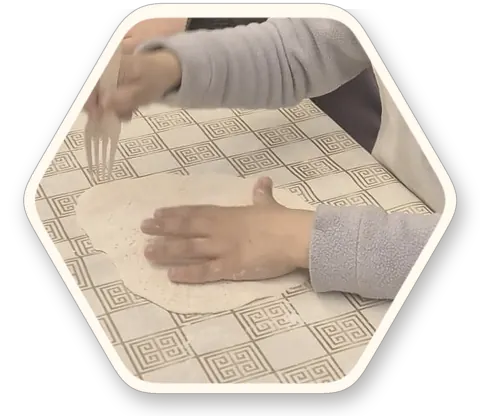 ידיו של ילד משטחות בצק על השולחן, בסדנת אפייה