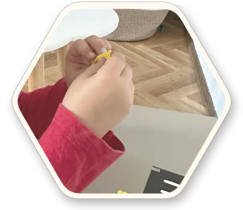 ידיה של ילדה בונות אות מבצק צבעוני, לצד כרטיס האות