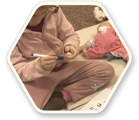 ילדה יושבת על השטיח עם המגש והחומרים שלה